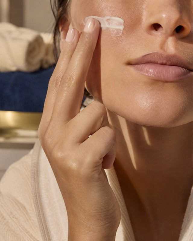 Fingers pressing moisturizer onto the cheek while the skin around the mouth is left bare